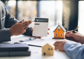 House model with agent and customer discussing for contract to buy, get insurance or loan real estate or property.